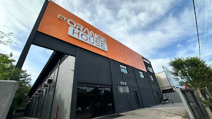 Fachada industrial preta do CT Orange House com letreiro laranja